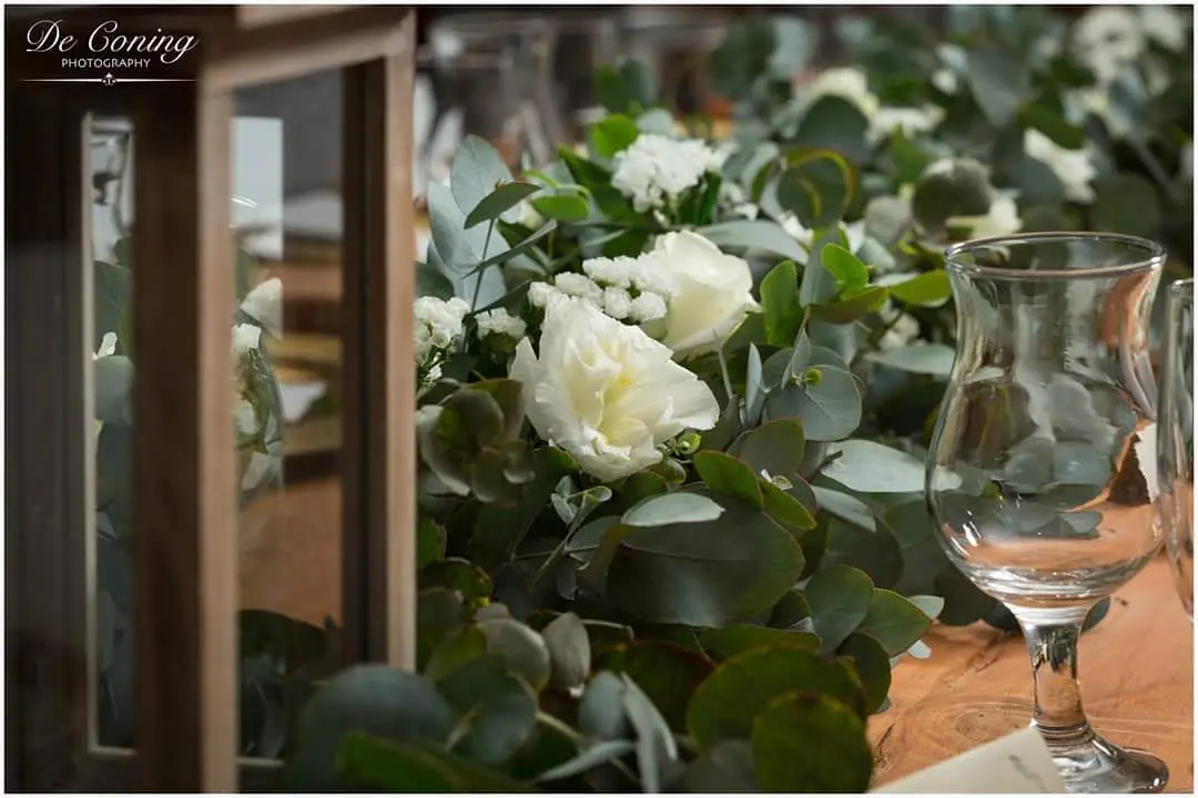 Reception banquet table setting with citrus accents and tall greenery arrangements