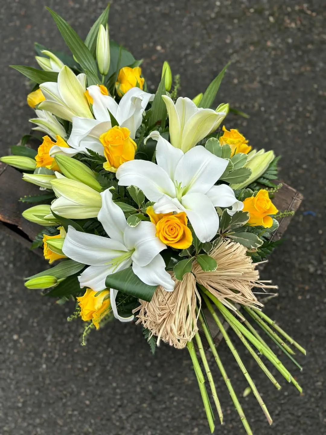 Sheaf of white lilies and yellow roses tied with raffia