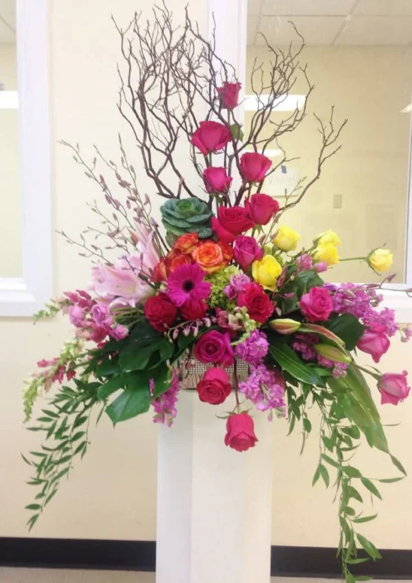 Bright pink and yellow flowers with branches on a white stand