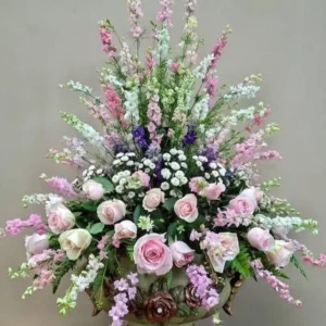 Pink roses and delphinium arrangement in an urn