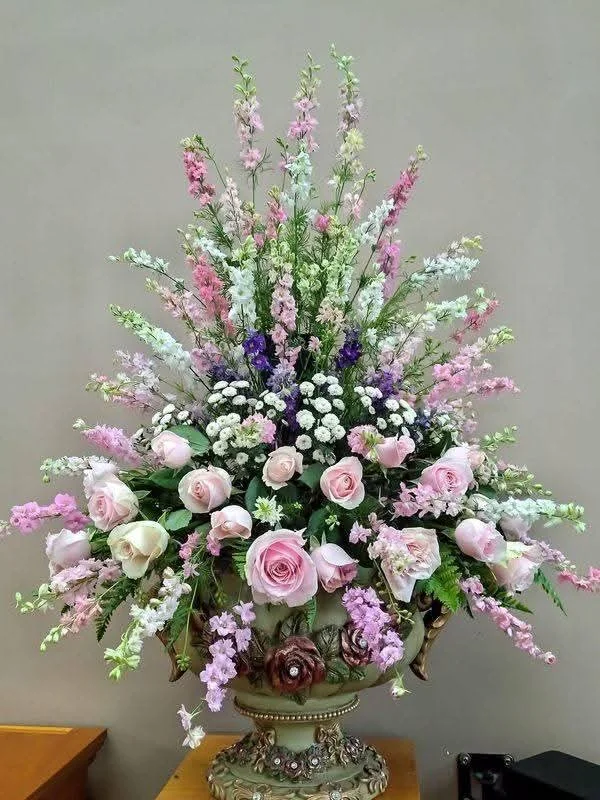 Pink roses and delphinium arrangement in an urn